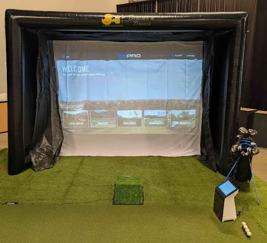 The new compact 12-foot Birdies & Brews inflatable golf simulator bay set up indoors with hitting mat, launch monitor and clubs.